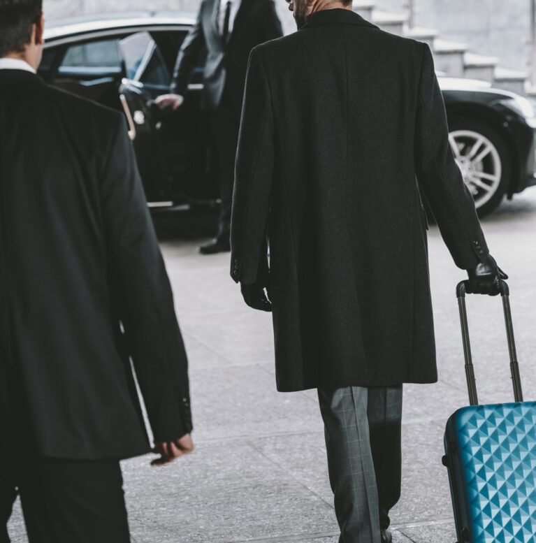 businessman going with blue travel bag to car